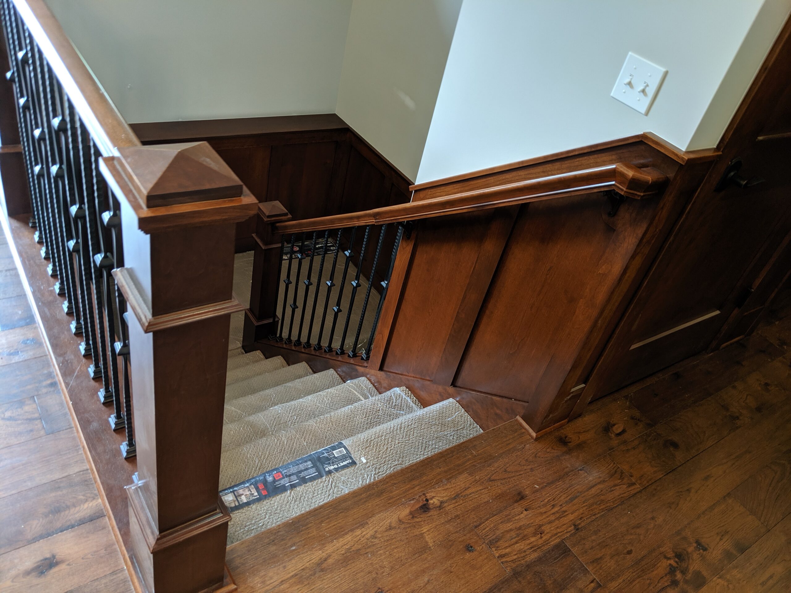 Custom dark walnut staircase with iron balusters and wainscoting